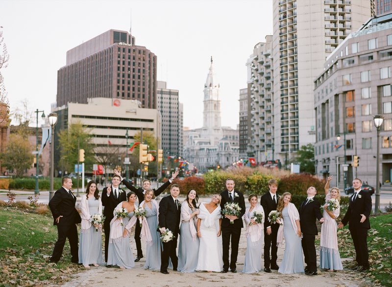 Full bridal party celebrating on a Philadelphia street with City Hall in the background